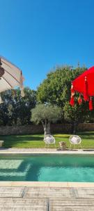 two chairs and an umbrella next to a swimming pool at Le Clos Des Cambres in Les Arcs sur Argens