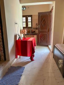 ein Zimmer mit einem Tisch mit einem roten Tischtuch darauf in der Unterkunft Leela Hatha in Rishikesh