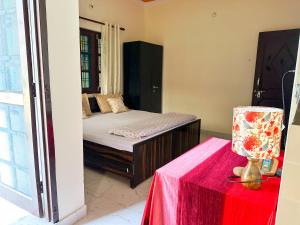 ein Schlafzimmer mit einem Bett und einem Tisch mit einem roten Tuch in der Unterkunft Leela Hatha in Rishikesh