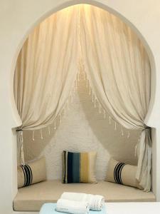 um quarto com uma cama com uma cortina e almofadas em Hôtel Djerba Authentique - Au centre de Midoun em Midoun