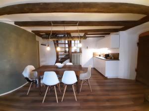 魏因海姆的住宿－Historischer Adelshof am Marktplatz, Atelier 70 m²，一间带木桌和白色椅子的用餐室