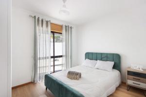 Schlafzimmer mit einem Bett mit einem grünen Kopfteil und einem Fenster in der Unterkunft Gilove House in Póvoa de Varzim