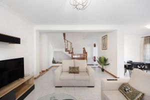 sala de estar con muebles blancos y TV de pantalla plana en Gilove House en Póvoa de Varzim