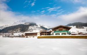 domek narciarski na śniegu obok zamarzniętego jeziora w obiekcie Chalet Matzhof w mieście Leogang