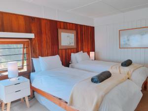 1 dormitorio con 2 camas, mesa y ventana en Timber's Ocean House, en Simonʼs Town