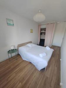 Schlafzimmer mit einem weißen Bett und Holzboden in der Unterkunft L'Edison *T3* proche hôpital in Orléans