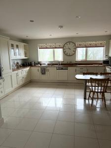a large white kitchen with a clock on the wall at Riverview Cottage in Gortnessy Upper