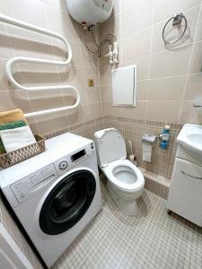 een wasmachine in een badkamer met een toilet bij Сеть BRAUN Сатпаева 11 in Pavlodar