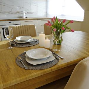 a wooden table with plates and candles and flowers on it at Apartamenty u Roxi in Jelenia Góra