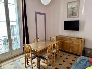 a dining room with a table and chairs and a television at APPARTEMENT MAISON, CENTRE VILLE, PROCHE PLAGE TOUT COMMERCE in Menton