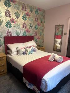 a bedroom with a large bed with a red blanket at The Savoy in Skegness