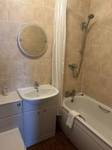 ein Badezimmer mit einem Waschbecken, einer Badewanne und einem Spiegel in der Unterkunft The Savoy in Skegness