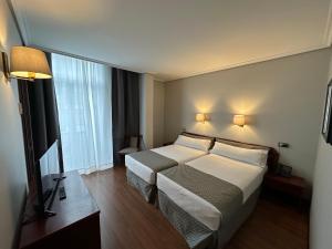 a hotel room with a bed and a television at Hotel Compostela Vigo in Vigo