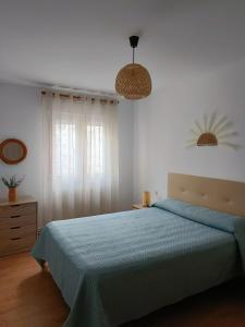 a bedroom with a blue bed and a window at Apartamento La Planchada in El Astillero