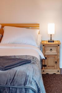 ein Schlafzimmer mit einem Bett und einem Nachttisch mit einer Lampe in der Unterkunft Spacious Flat with Free Parking in Harrogate