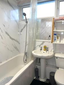 ein weißes Bad mit einem Waschbecken und einer Dusche in der Unterkunft Impeccable Spacious 6-Bed House in Romford in Romford