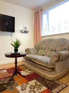 ein Wohnzimmer mit einem Sofa und einem Tisch in der Unterkunft Impeccable Spacious 6-Bed House in Romford in Romford