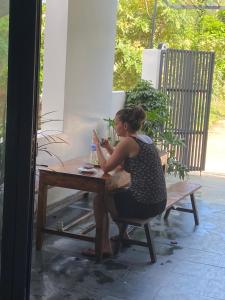 a woman sitting at a table looking at her cell phone at Ju’s House in Dong Hoi