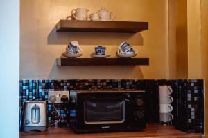 a microwave in a kitchen with a shelf above it at Spacious Flat with Free Parking in Harrogate