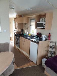 a small kitchen with a stove and a microwave at 3 bed static caravan in Chapel Saint Leonards