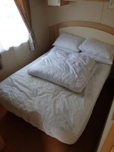 an unmade bed in a room with a window at 3 bed static caravan in Chapel Saint Leonards