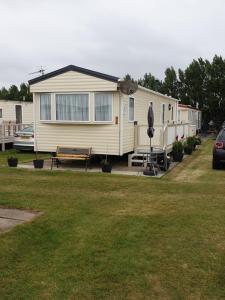 a mobile home with a bench in a yard at 3 bed static caravan in Chapel Saint Leonards