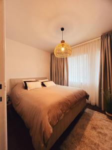a bedroom with a large bed and a chandelier at Studio Bella in De Panne