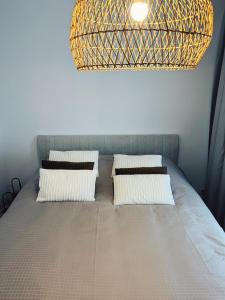 a room with a bed with pillows and a chandelier at Studio Bella in De Panne