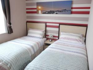 two beds in a room with red and white stripes at Melbourne Guest House in Rhyl