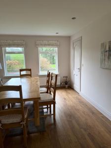 uma sala de jantar com uma mesa e cadeiras e duas janelas em Riverview Cottage em Gortnessy Upper