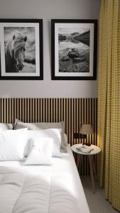 ein Schlafzimmer mit einem weißen Bett und Bildern an der Wand in der Unterkunft Hotel Etropol, Center Etropole in Etropole