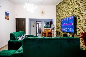 una sala de estar con sofás verdes y una pared de piedra. en Stunning 4-Bed Villa in cocody engre Abidjan en Cocody