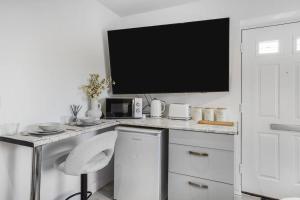 a white kitchen with a desk with a tv on it at Little Laxford in Fazeley