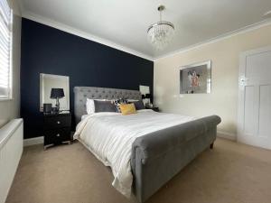 a bedroom with a large bed with a blue wall at Luxury 4 Bed 2 Bath House with Garden near Wimbledon in London