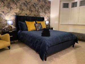 a bedroom with a bed with blue sheets and yellow pillows at Luxury 4 Bed 2 Bath House with Garden near Wimbledon in London
