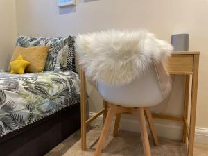 a white chair sitting next to a table with a couch at Luxury 4 Bed 2 Bath House with Garden near Wimbledon in London