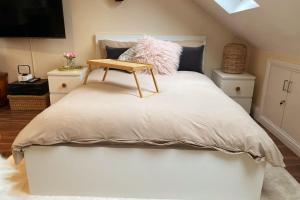 a bed with a wooden table on top of it at Luxury 4 Bed 2 Bath House with Garden near Wimbledon in London