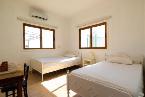 een slaapkamer met 2 bedden, een bureau en 2 ramen bij Captivating 2-Bed House in Alaminos