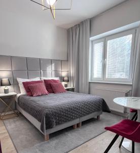 Apartamenty Pokoje Willa Bielany في وارسو: غرفة نوم بسرير كبير ومخدات حمراء