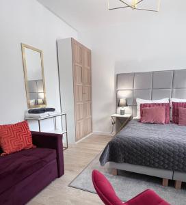 a bedroom with a bed and a chair and a mirror at Apartamenty Pokoje Willa Bielany in Warsaw