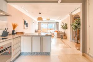 a kitchen with white cabinets and a living room at Stylish Apartment Aloha Hill Club Marbella - TCM in Marbella