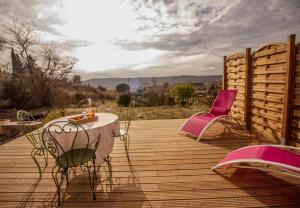 Gite la Canague Neuve في Montady: سطح خشبي مع طاولة وكرسي وردي