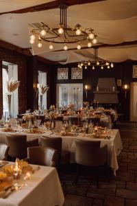 une salle à manger avec des tables blanches, des chaises et des lumières dans l'établissement Gut Dyckhof, à Meerbusch