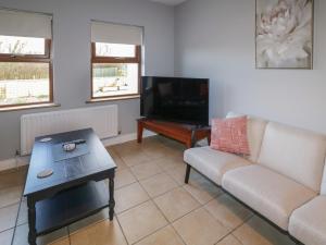 a living room with a couch and a flat screen tv at The Garden Cottage in Crossmaglen