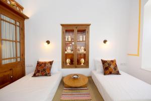 una camera con due letti bianchi e un tavolo in legno di Villa Annoula - Traditional Lindian House a Líndos