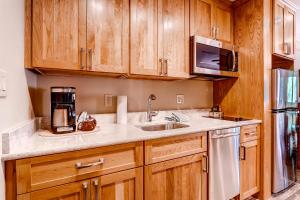 cocina con armarios de madera, fregadero y microondas en Mountain House by Keystone Resort, en Keystone