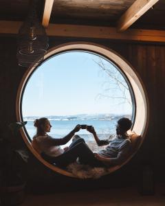 a man and a woman sitting in a round window at Fuglekassehytta 