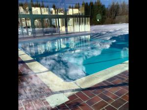 una piscina con reflejo de un edificio en Chalet L’Embellie - Chalet avec piscine partagée, en Saint-Laurent-en-Grandvaux