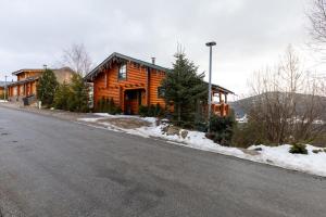 a wooden house on a street next to a road at Le Chalet des Ours - Superbe chalet 4 étoiles in Les Angles