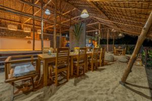 a restaurant with wooden tables and chairs in the sand at Komba Cabana in Nosy Komba